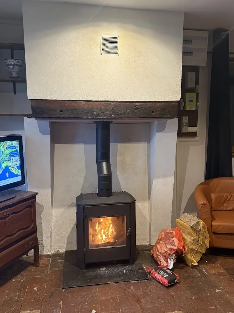 Poêle à bois allumé avec flamme visible dans un intérieur du Loiret